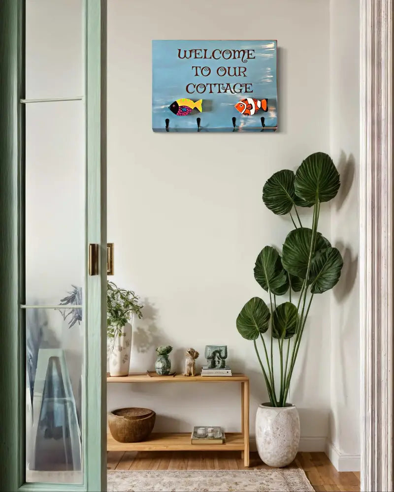 Cottage folk art sign with hooks, featuring "Welcome to Our Cottage" engraving and colorful fish motifs on wood.