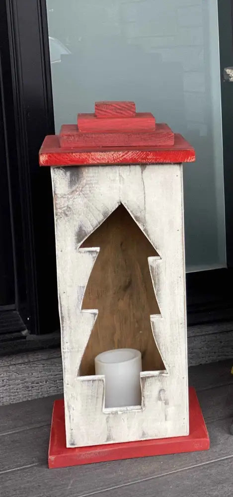 Handcrafted wooden lantern with tree design and candle inside.