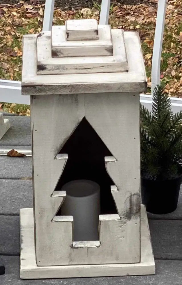 Handcrafted wooden lantern with tree design for indoor and outdoor decor.