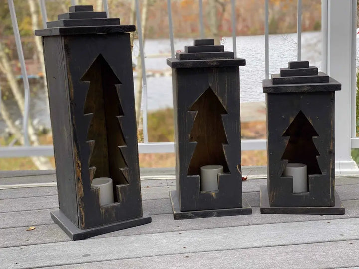 Handcrafted wooden lanterns with tree design on a porch.