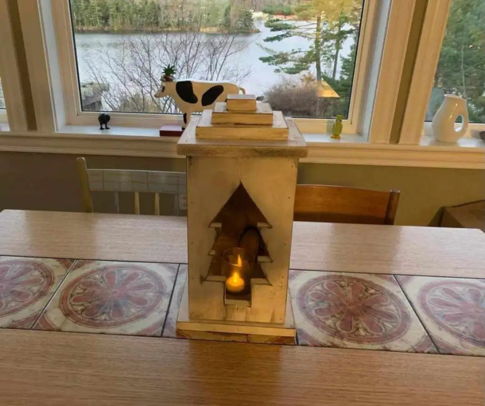 Handcrafted wooden lantern on a table with a scenic outdoor view.