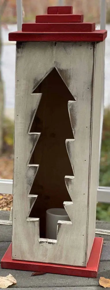 Handcrafted wooden lantern with intricate tree design and red accents.