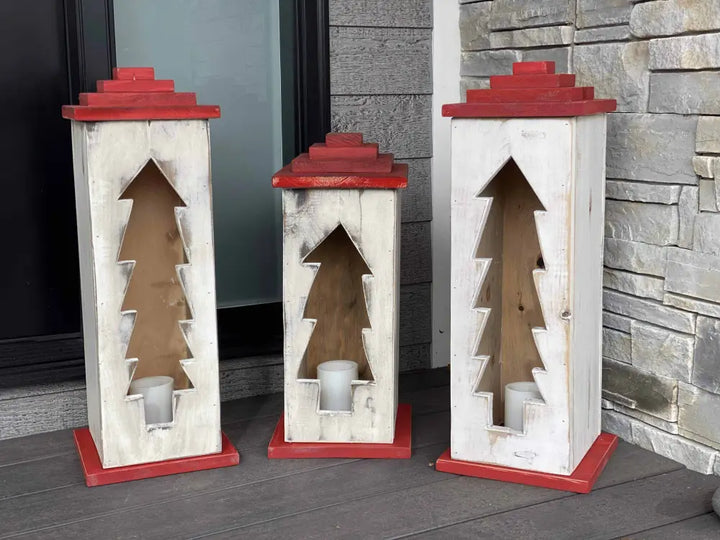 Handcrafted wooden lanterns with tree pattern designs and red accents.