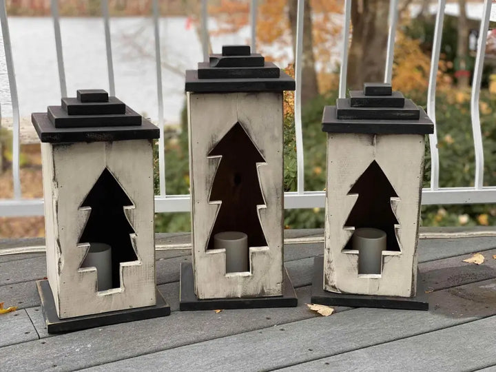 Handcrafted wooden lanterns with tree cutout design on porch.
