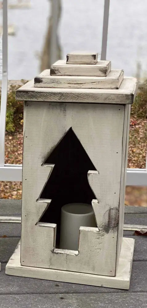 Handcrafted wooden lantern with tree cut-out design for home decor.