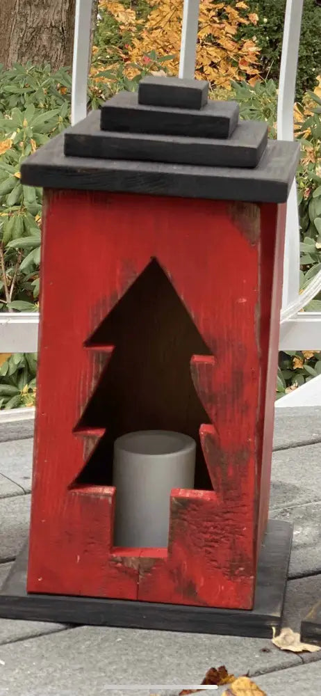 Handcrafted red wooden lantern with tree cut-out design for cozy ambiance.