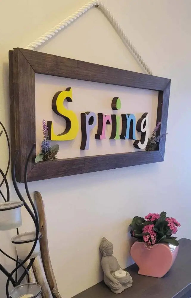 Handmade wooden sign with colorful spring letters, featuring rope attachment for easy hanging.