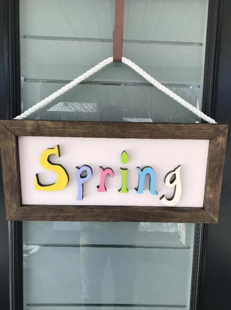 Handmade wooden sign with colorful "Spring" letters and rope hanging attachment.