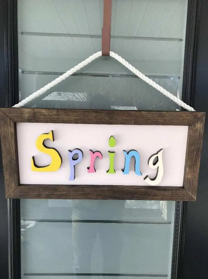 Handmade wooden sign with colorful "Spring" letters and rope hanging attachment.