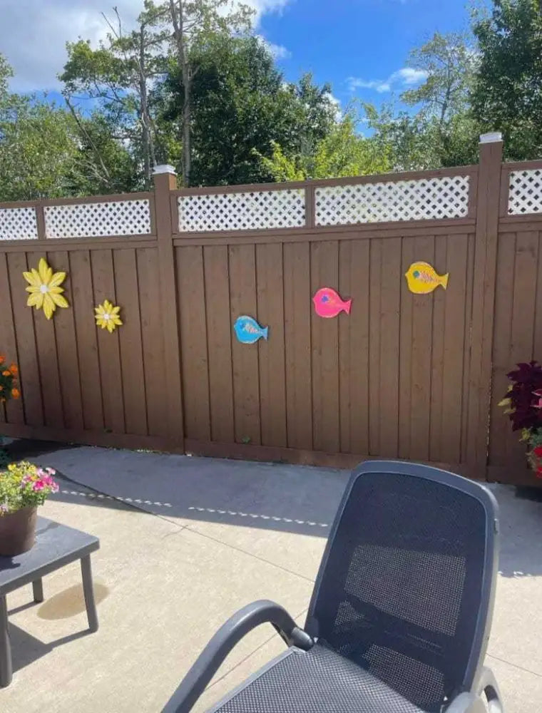 Hand painted folk art fish on a wooden fence in vibrant colors.
