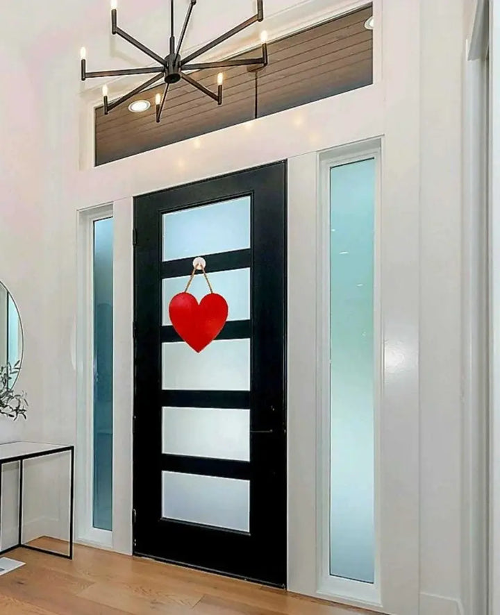Handcrafted wooden hearts wall art hanging on a modern black door in a bright entryway.