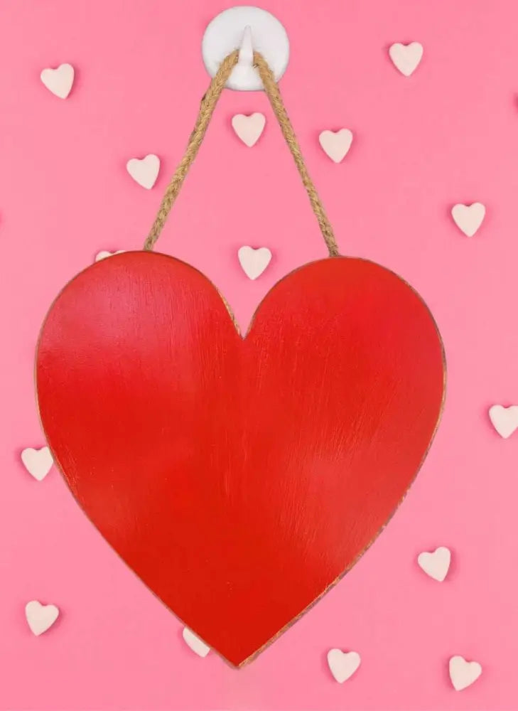 Red handcrafted wooden hearts wall art with attached hanger on a pink background.