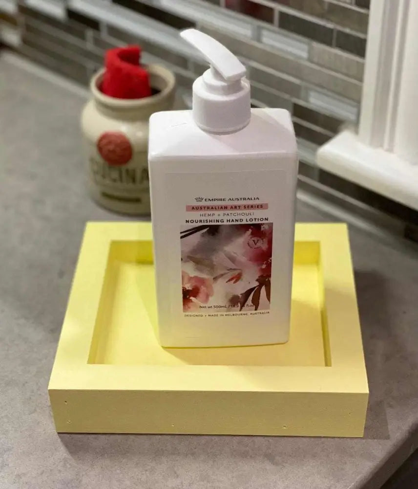 Yellow handcrafted pine soap dish holding a bottle on a gray countertop.
