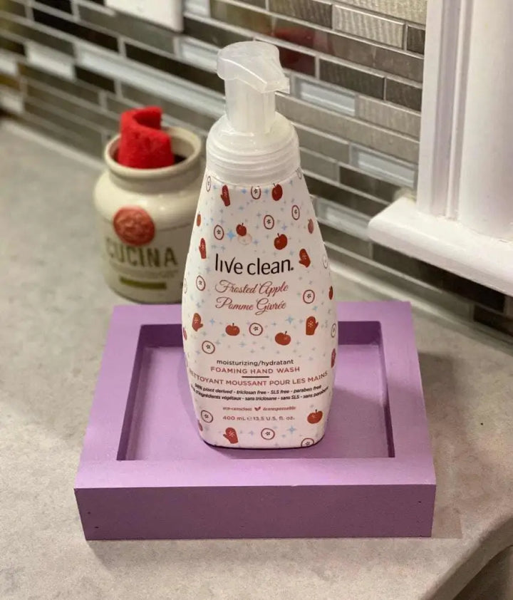 Purple handcrafted pine soap dish holding a bottle of foaming hand wash on a countertop.