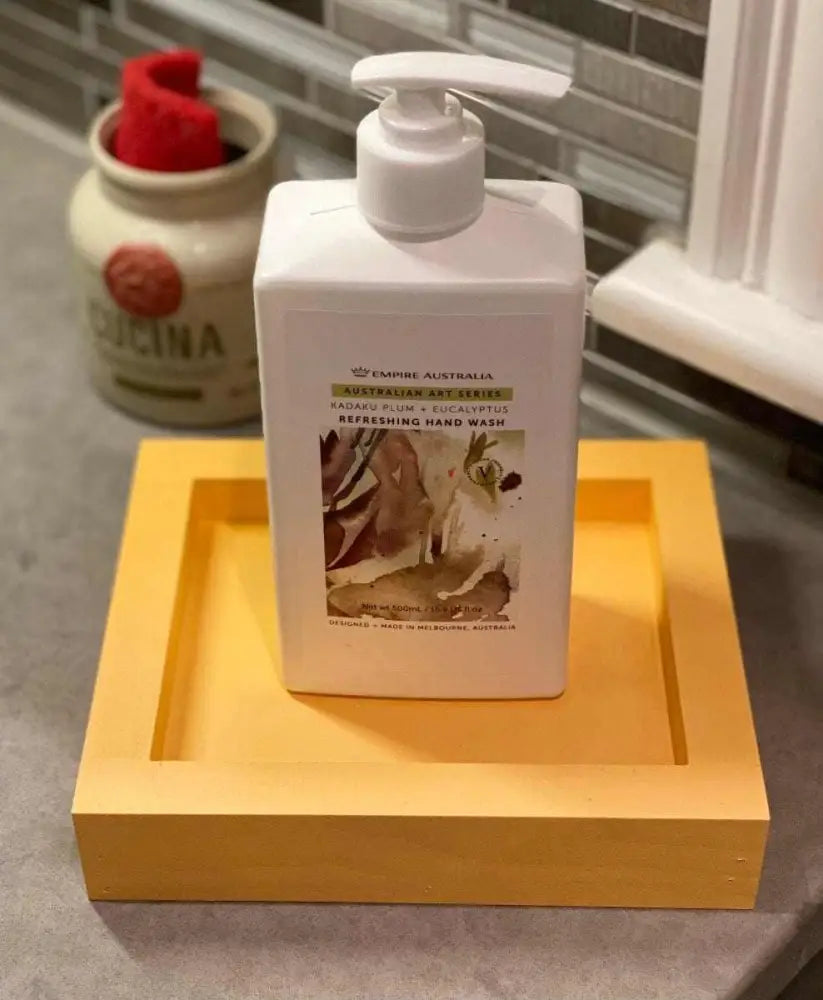 Handcrafted yellow pine soap dish holding a pump bottle on a bathroom counter.