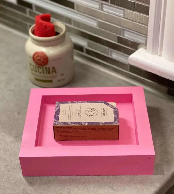 Pink handcrafted pine soap dish with soap bar on kitchen counter.