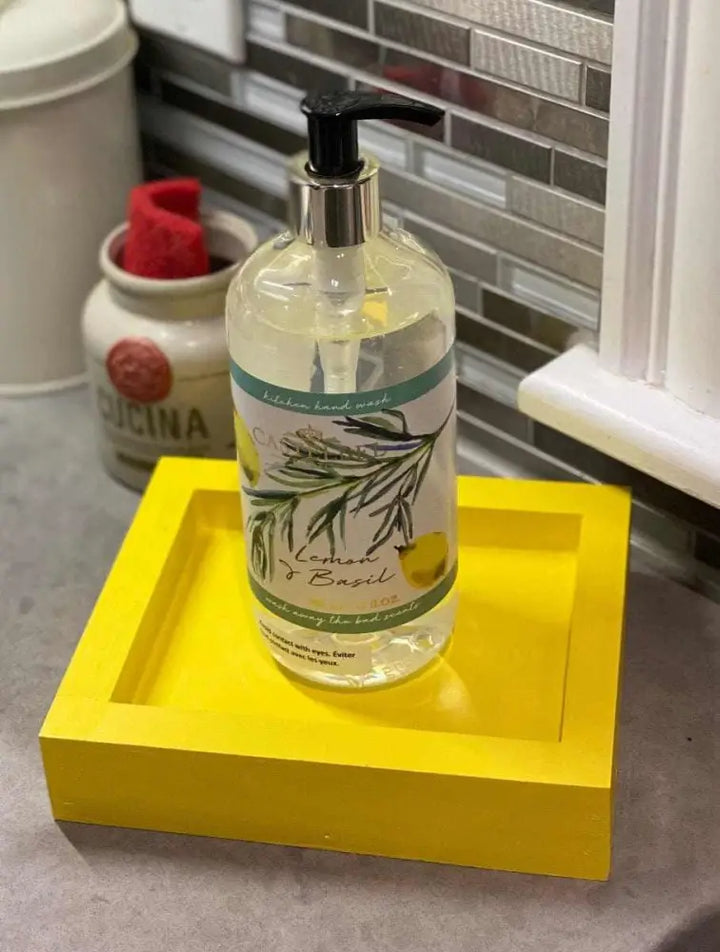 Handcrafted pine soap dish in vibrant yellow holding a lemon basil hand soap bottle on a kitchen counter.
