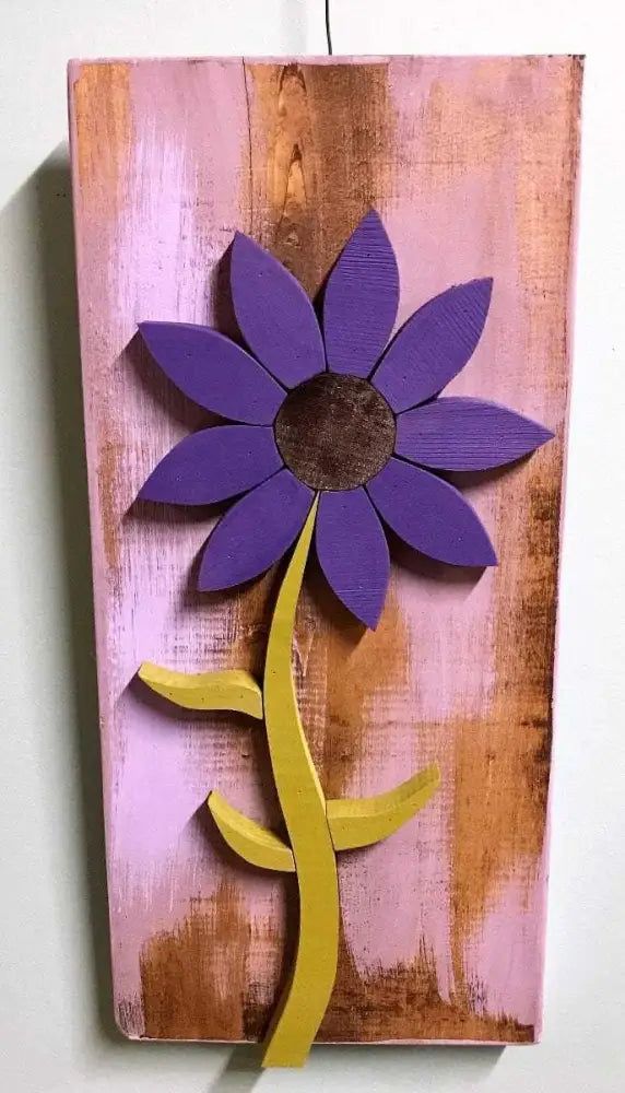 Handcrafted purple wooden flower wall art with yellow stem on distressed pink and brown background