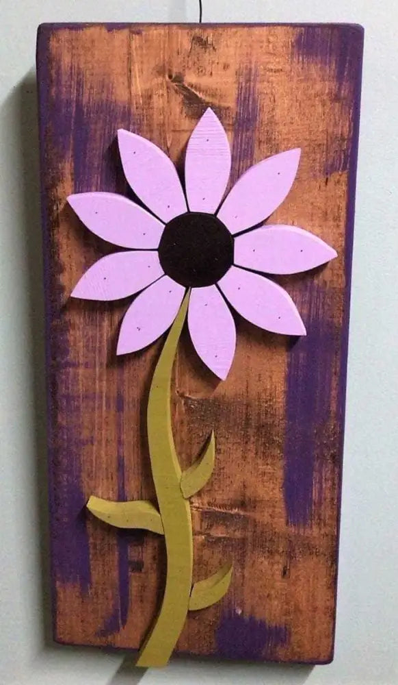 Handcrafted pine wood wall art flower with purple petals and green stem on distressed wooden background