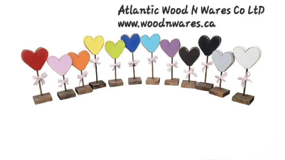 Colorful handcrafted wooden hearts with bows on wooden stands, by Atlantic Wood N Wares Co Ltd.