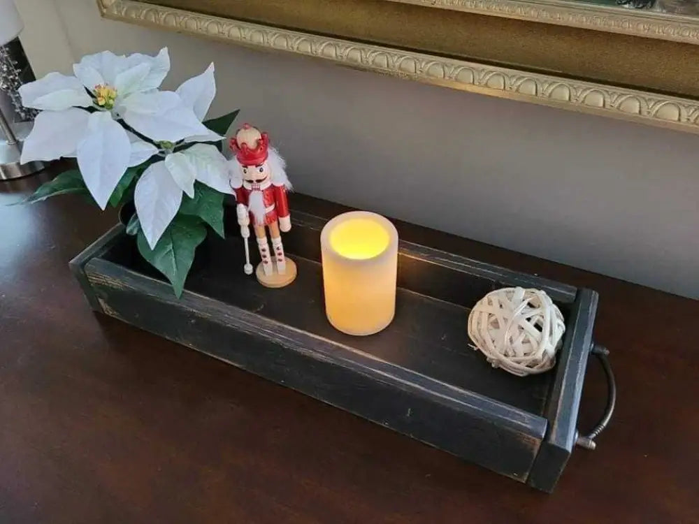 Antiqued wooden trays with handles, displaying decor items on a table.