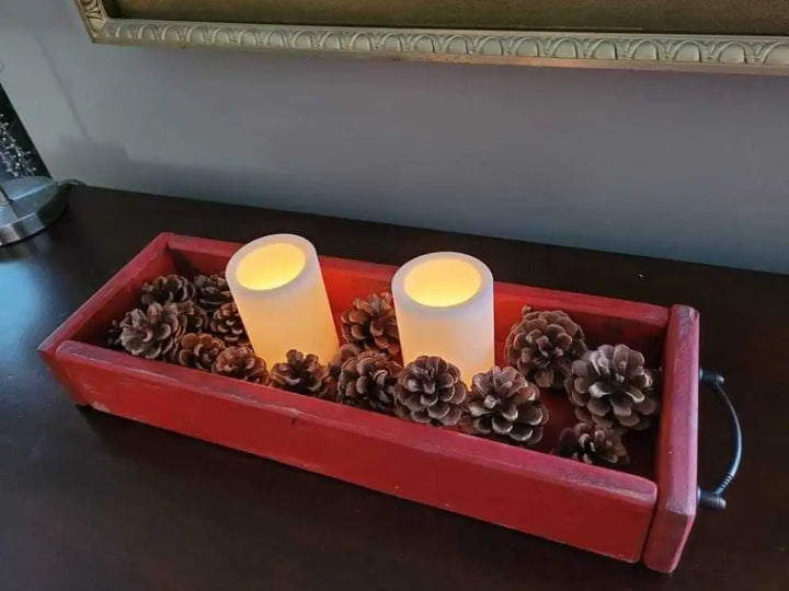 Antiqued wooden trays with handles featuring rustic finish, adorned with candles and pinecones for elegant decor.