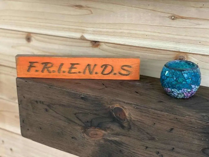 Laser engraved wooden friendship sign on shelf with decorative item.