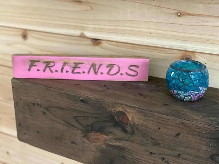 Laser engraved friendship sign on a wooden shelf.