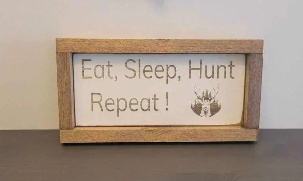 Laser engraved wood sign for hunters featuring the phrase "Eat, Sleep, Hunt, Repeat" with deer and forest design.