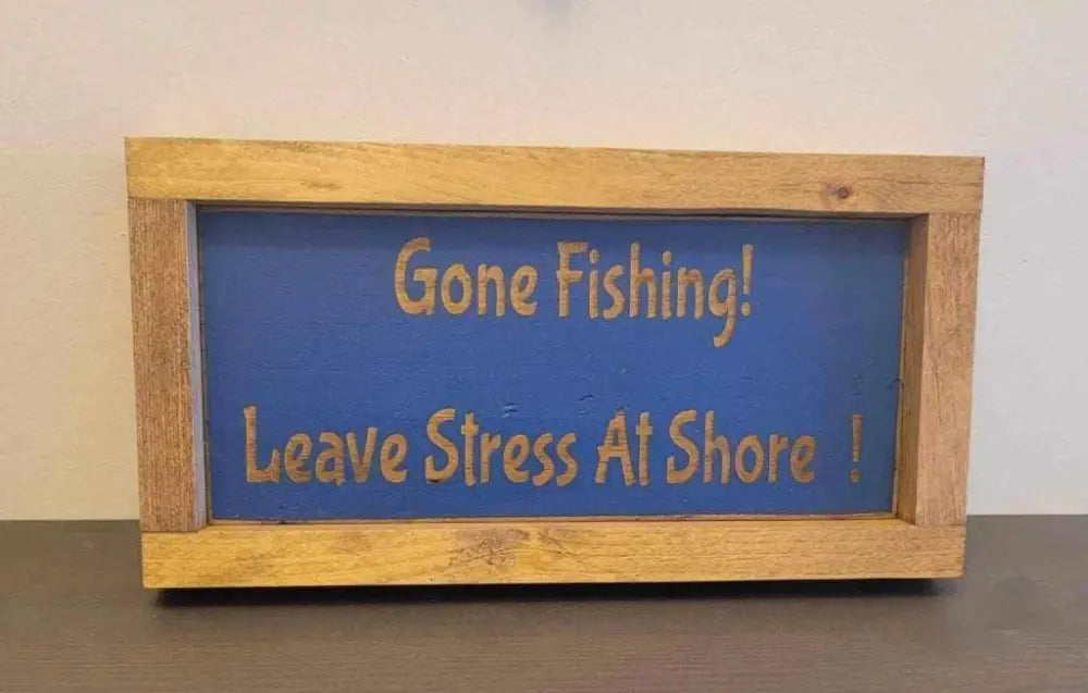 Laser engraved wood sign with the phrase "Gone Fishing! Leave Stress At Shore," ideal for outdoor lovers.