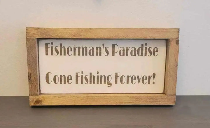 Laser engraved wood sign with "Fisherman's Paradise, Gone Fishing Forever" message for outdoor enthusiasts.