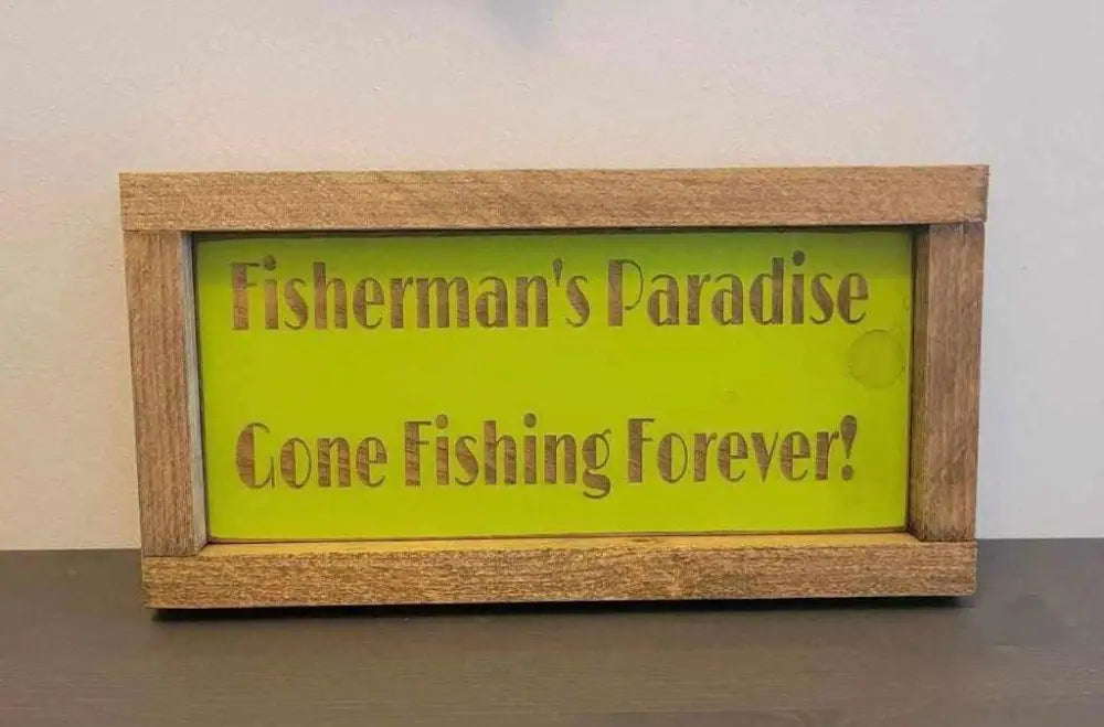 Laser engraved wood sign with "Fisherman's Paradise, Gone Fishing Forever" text, perfect for outdoor enthusiasts.