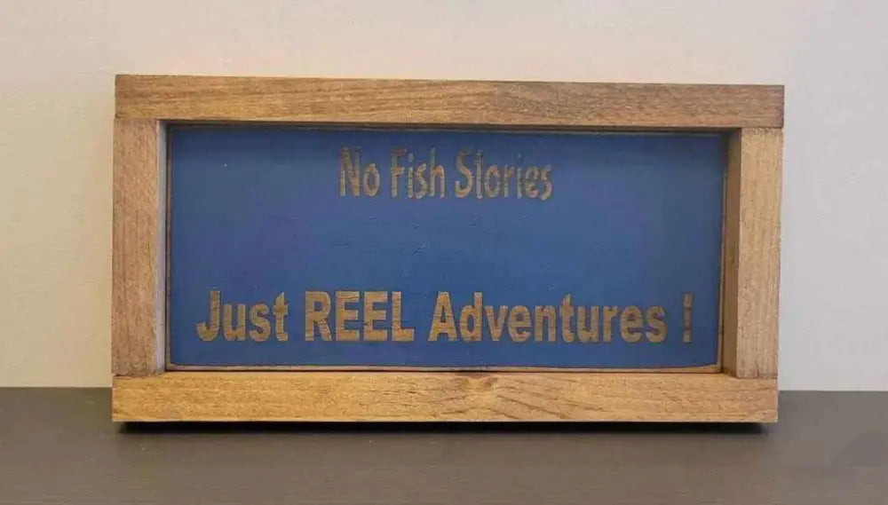 Laser engraved wood sign with "No Fish Stories, Just REEL Adventures" in rustic frame. Ideal for outdoor enthusiasts.