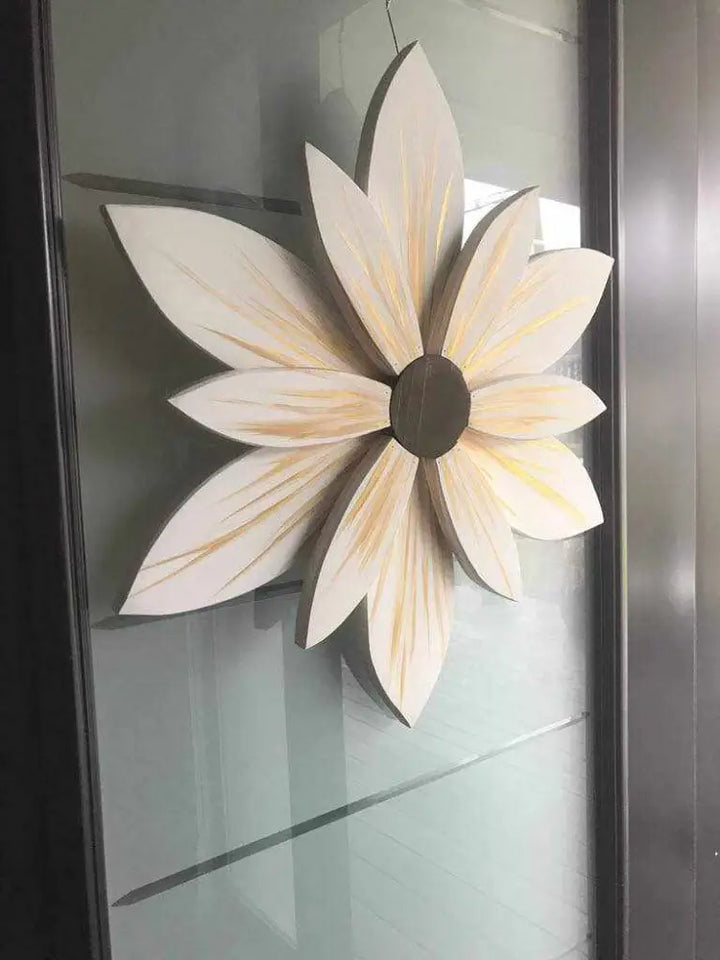 Handcrafted wooden flower art with white petals on glass door.