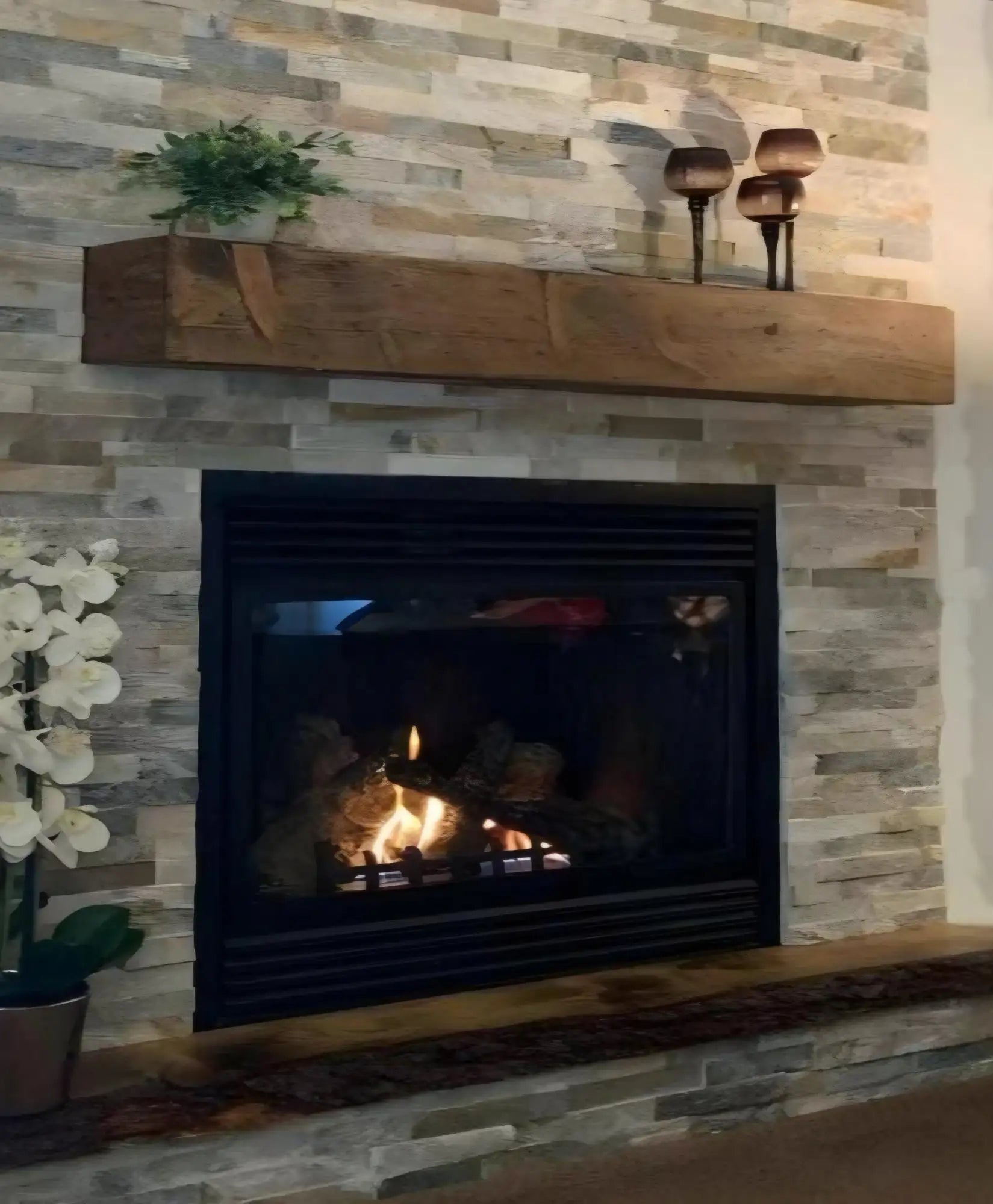 Modern black electric fireplace with wooden mantel and stone surround.