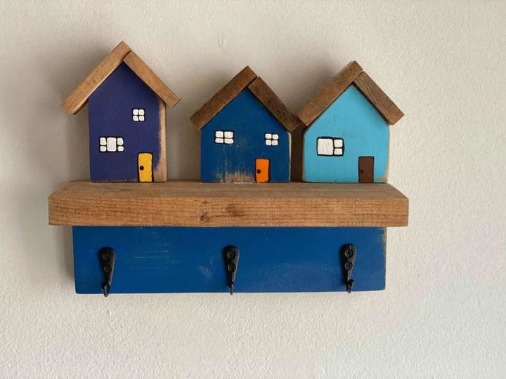 Wall mounted key chain holder with three house-shaped hooks.