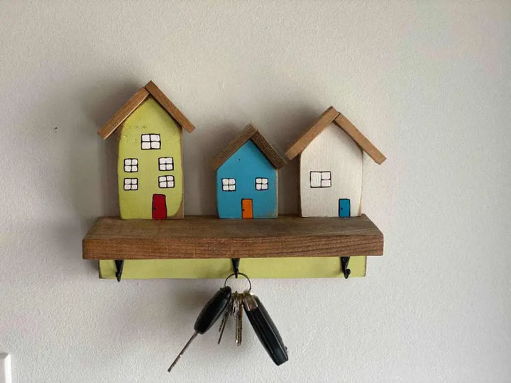 Wall mounted key chain holder with house design and three key hooks.