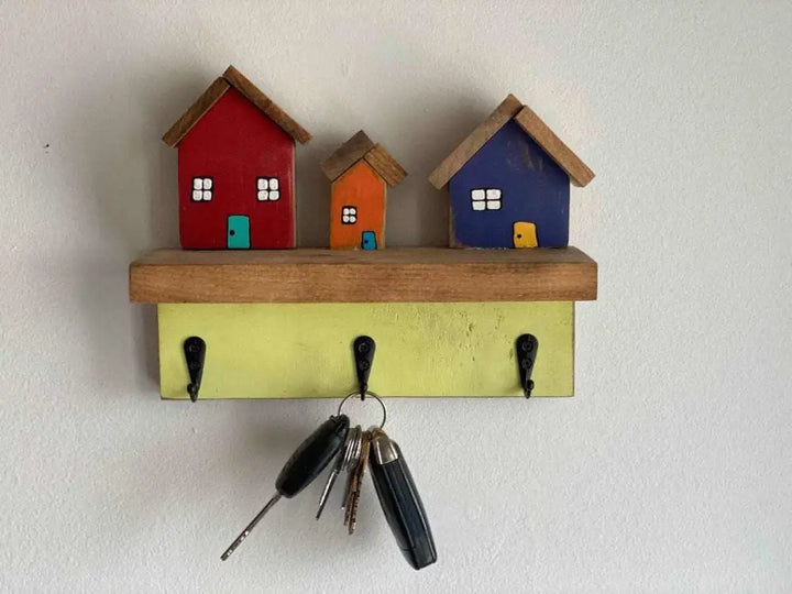 Wall mounted key chain holder with three hooks and colorful house design.