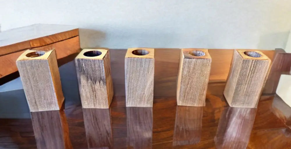Handcrafted maple wooden pen holders on a reflective surface.