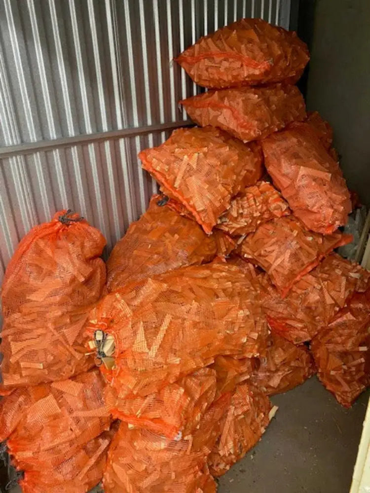 Pine wood kindling in large mesh bags for fireplaces, campfires, and stoves, stored indoors.