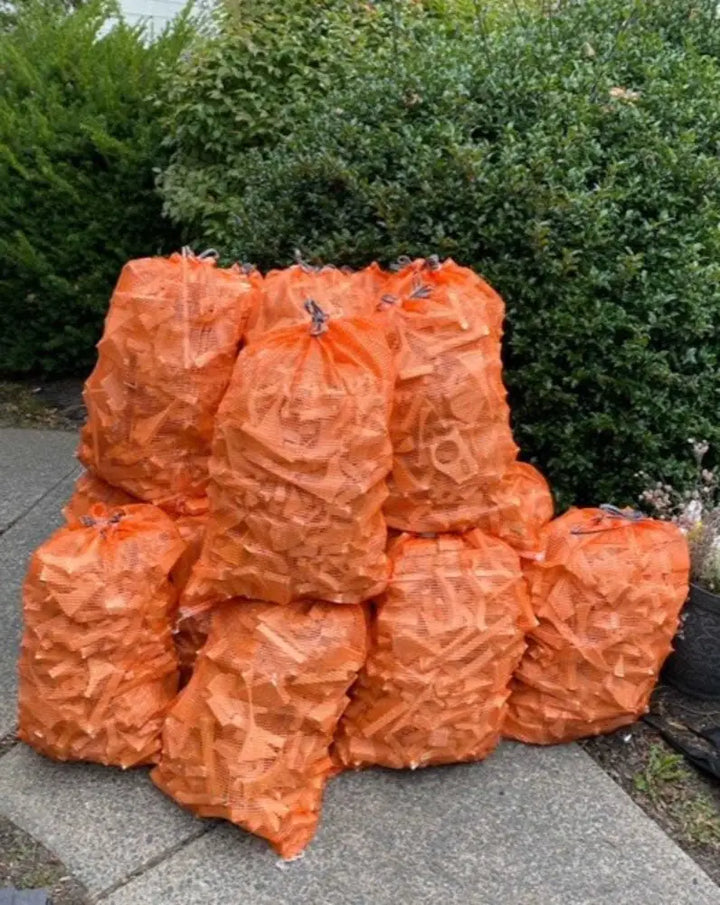 Pine wood kindling in orange mesh bags for fireplace, campfire, and stove.