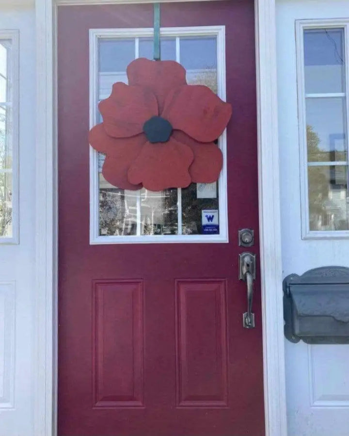 Handcrafted wooden flower door decor with anemone-inspired design, displayed on a red door.