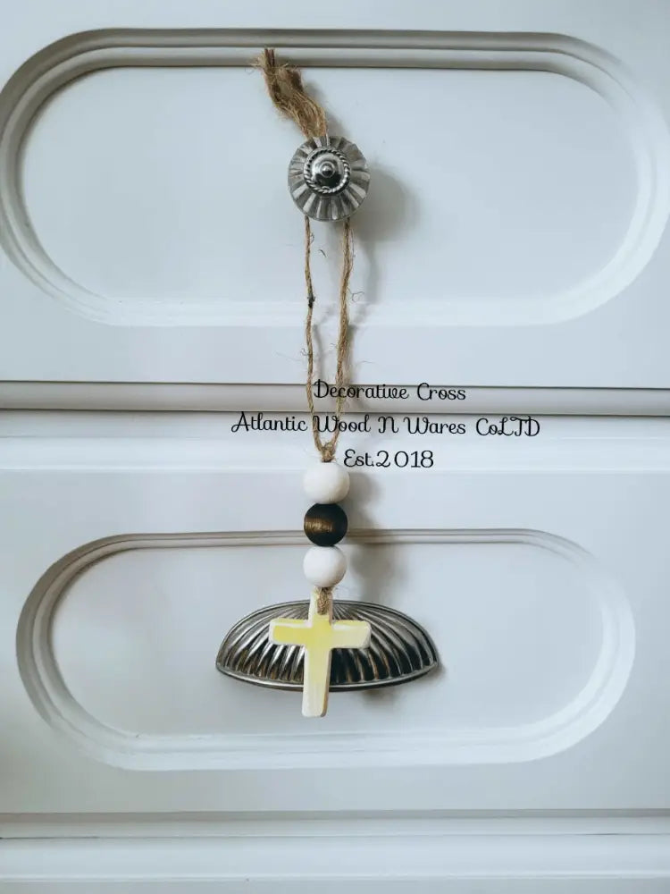 Rustic wooden bead and cross garland hanging on a white decorative surface.