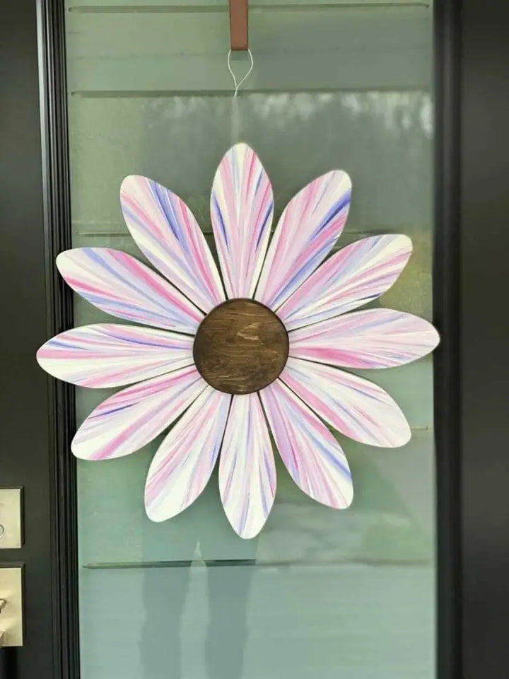Hand-painted wooden daisy flower art with pastel pink and purple petals hanging on a door, supporting the Sofia Daisy Campaign for children with congenital heart conditions in Canada.