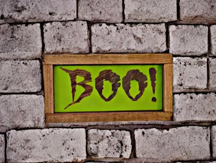  wood sign with "Boo!" text on a brick wall backdrop