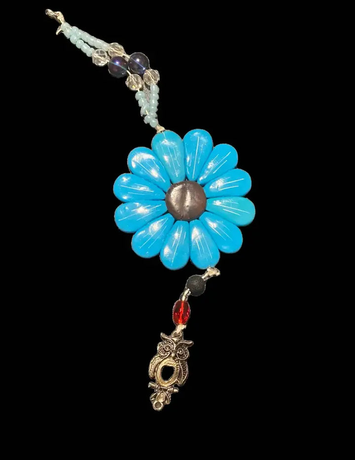 Blue Sofia Daisy Charm with polymer clay petals, black lava bead, and assorted glass beads, supporting IWK Foundation.