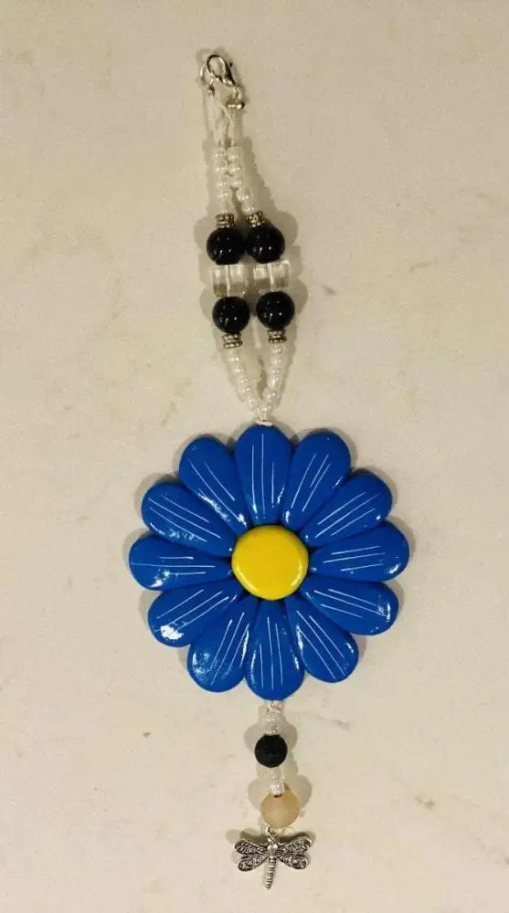 Blue Sofia Daisy car charm with yellow center, black lava beads, glass beads, and dragonfly pendant