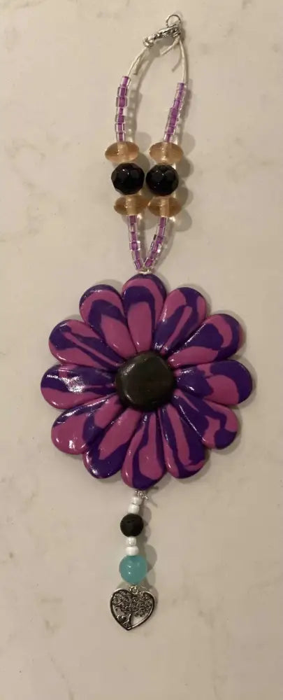 Purple Sofia Daisy car/window charm with black lava bead, glass accents, and elastic cord, supporting IWK Foundation.