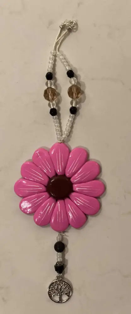 Hand-sculpted pink Sofia Daisy charm with glass and black lava beads, supporting IWK Foundation.
