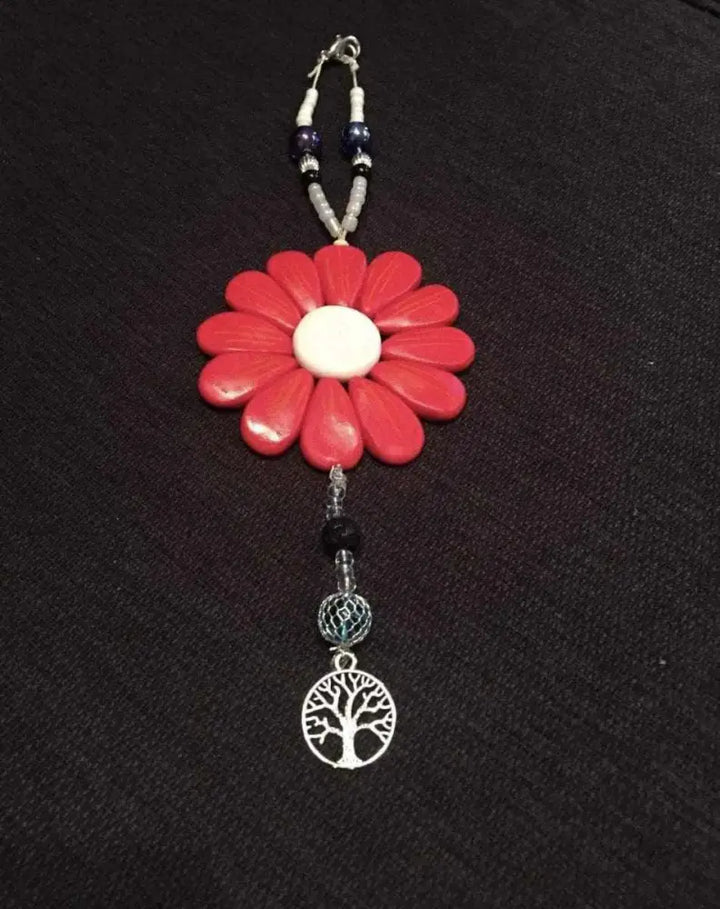 Sofia Daisy charm with red polymer petals, black lava bead, glass beads, and tree charm; supports IWK Foundation.